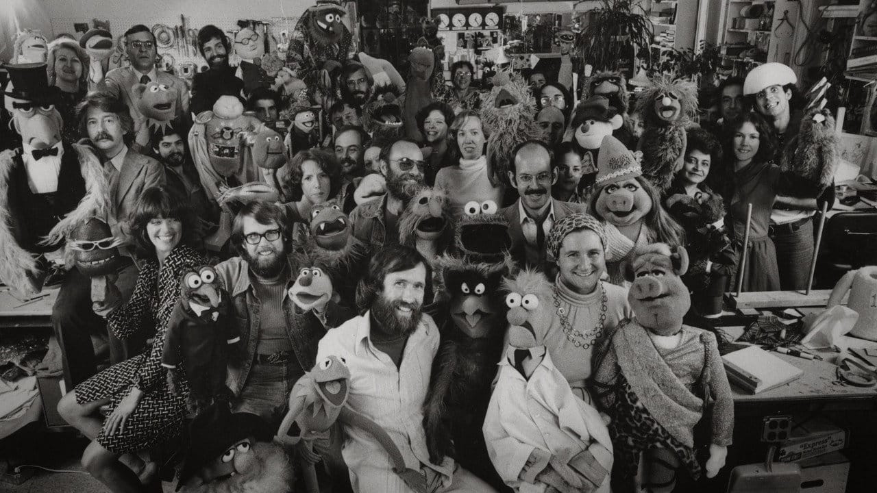 Jim Henson surrounded by his team of Muppet performers, builders and characters in the Muppet Show era