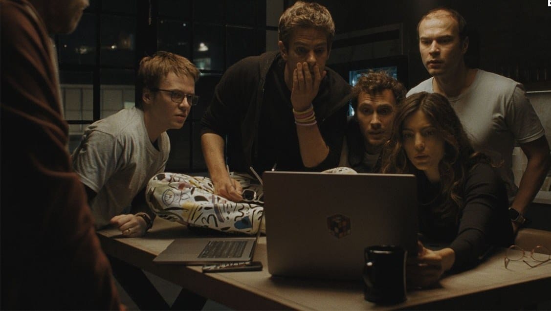 The cast of Artificial gathered around a laptop at night