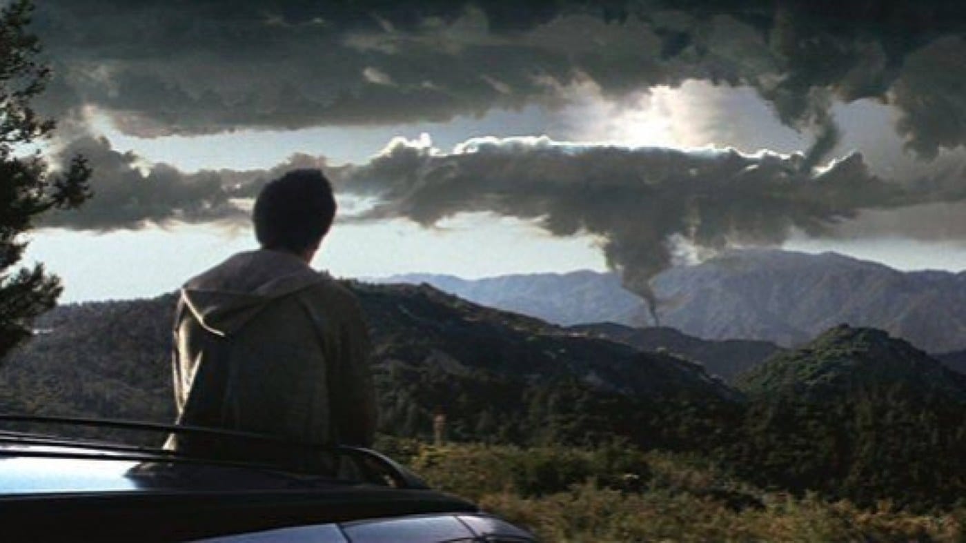 Donnie Darko standing on a hillside overlooking clouds and mountains