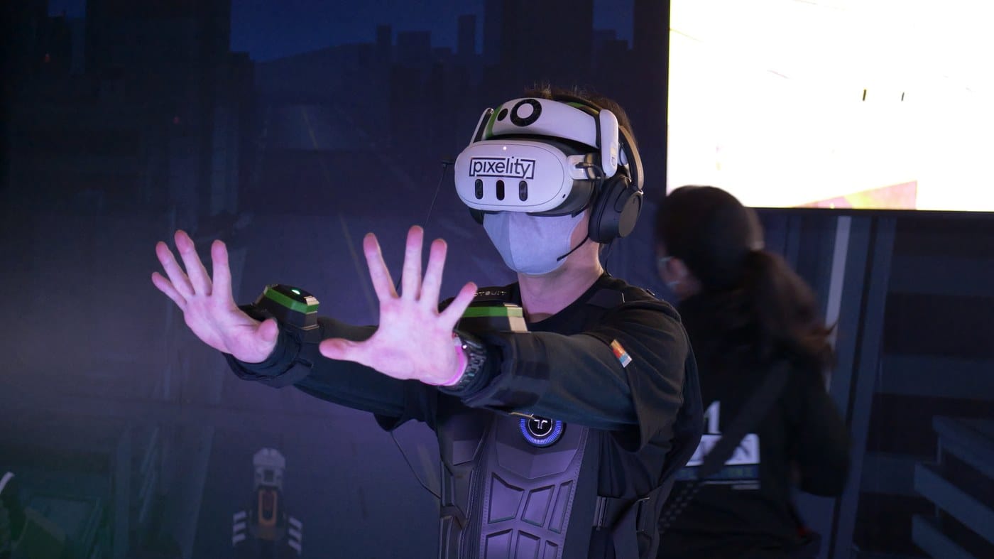 A player wearing a Pixelity headset and haptic vest tests the game with hand tracking