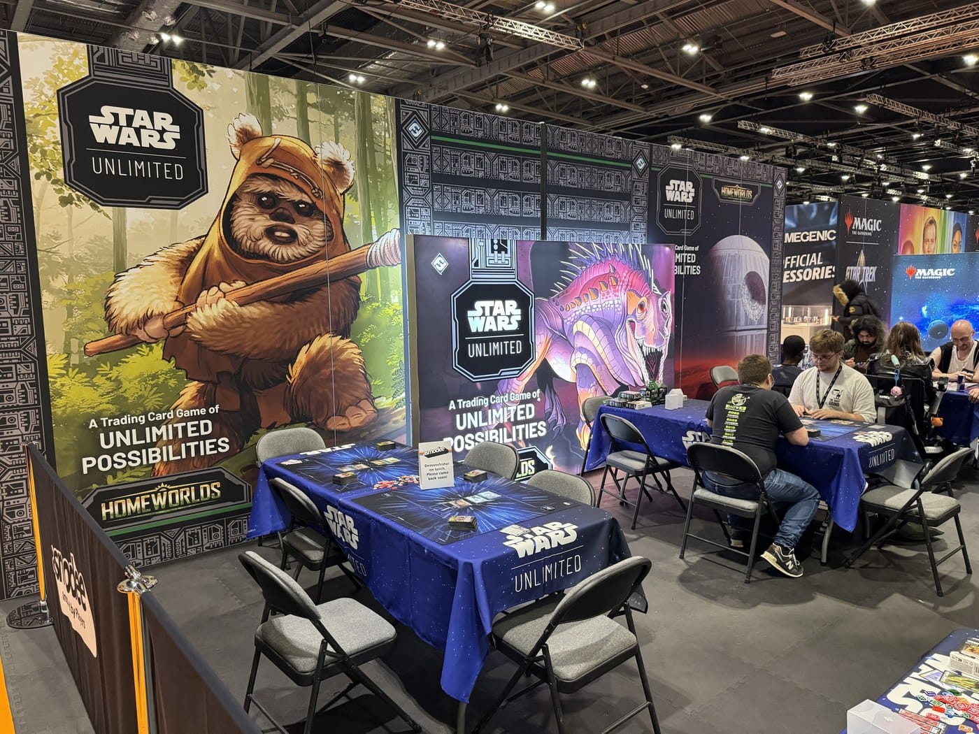The Star Wars: Unlimited demo area at MCM London, with Ewok and creature artwork for the Homeworlds set and players at blue Star Wars tables