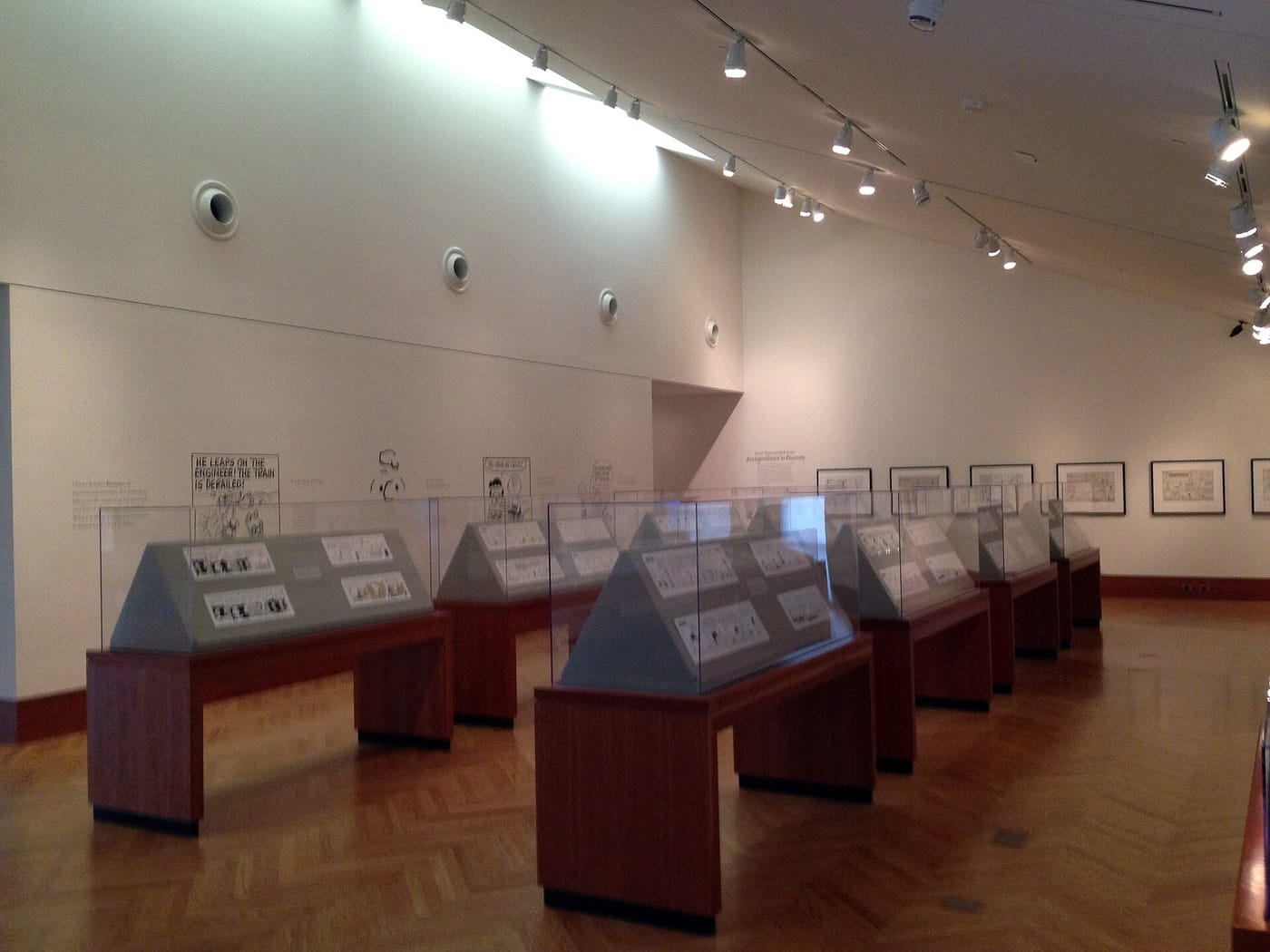 A gallery at the Charles M. Schulz Museum with display cases of original Peanuts strips