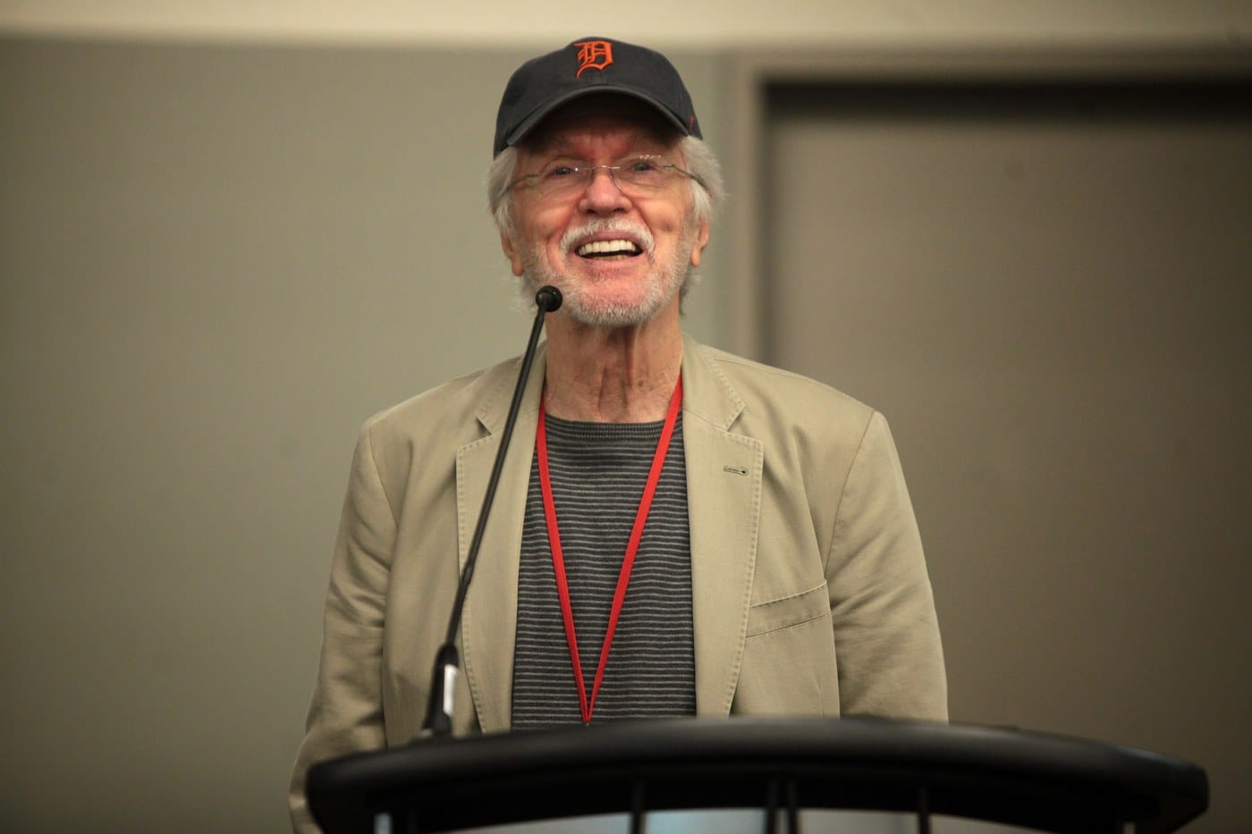 Tom Skerritt in a Detroit Tigers cap, smiling at a podium during a 2014 fan event in Arizona