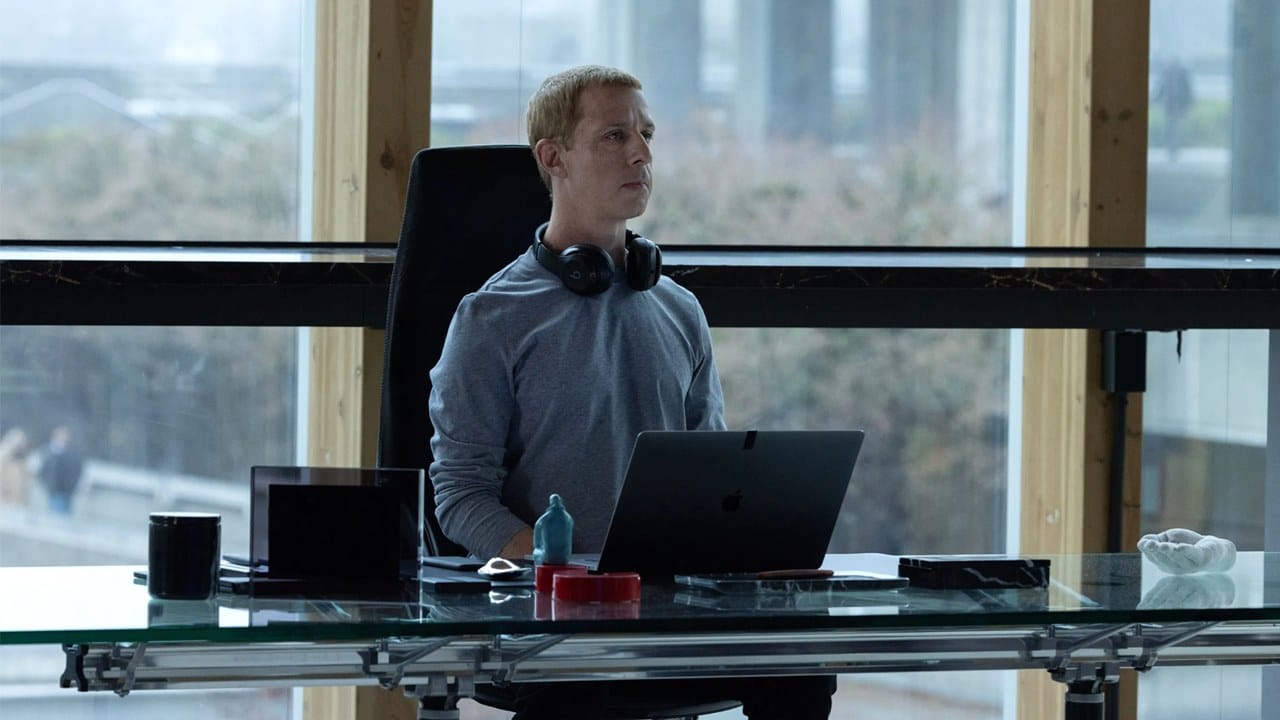 Jeremy Strong as Mark Zuckerberg at a glass desk in The Social Reckoning