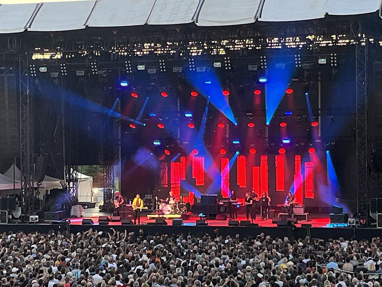 A large outdoor concert stage with red and blue lights during a Sting show