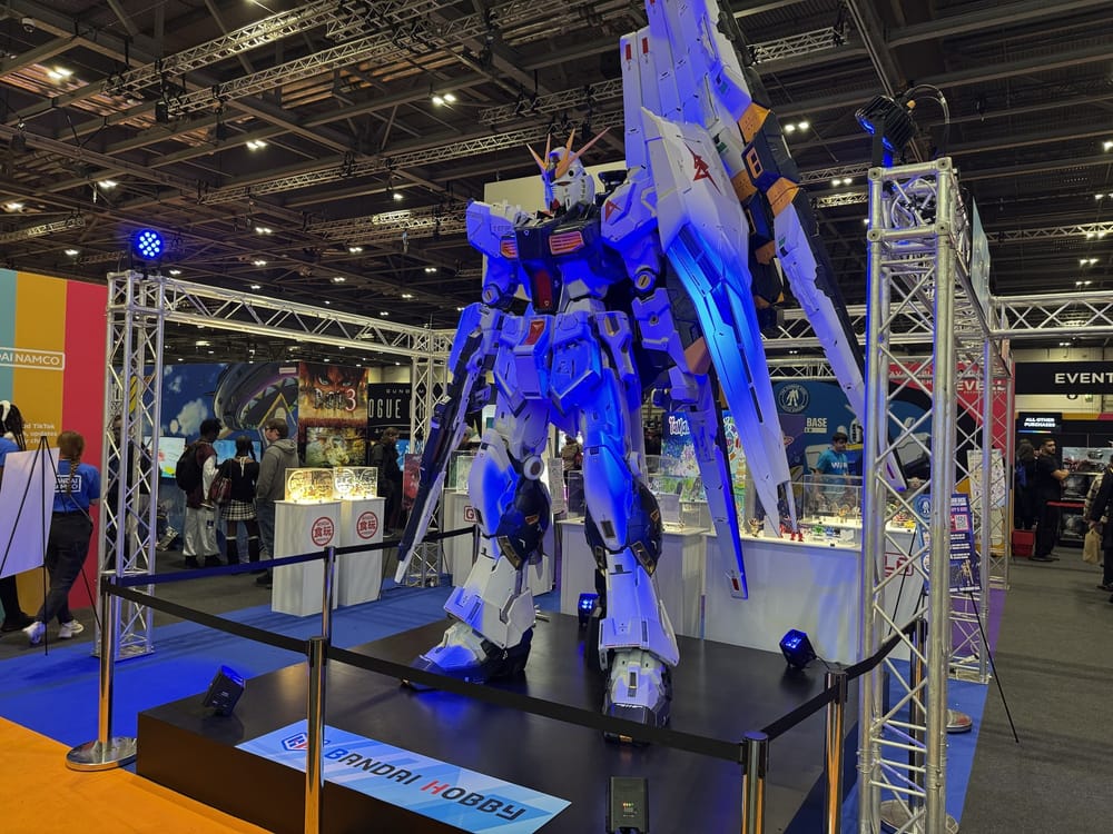 A life-size RX-93 ν Gundam statue lit in blue on the Bandai Hobby stand at MCM London Comic Con, ExCeL London