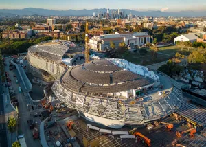 The Lucas Museum of Narrative Art at dusk, with the downtown Los Angeles skyline behind it